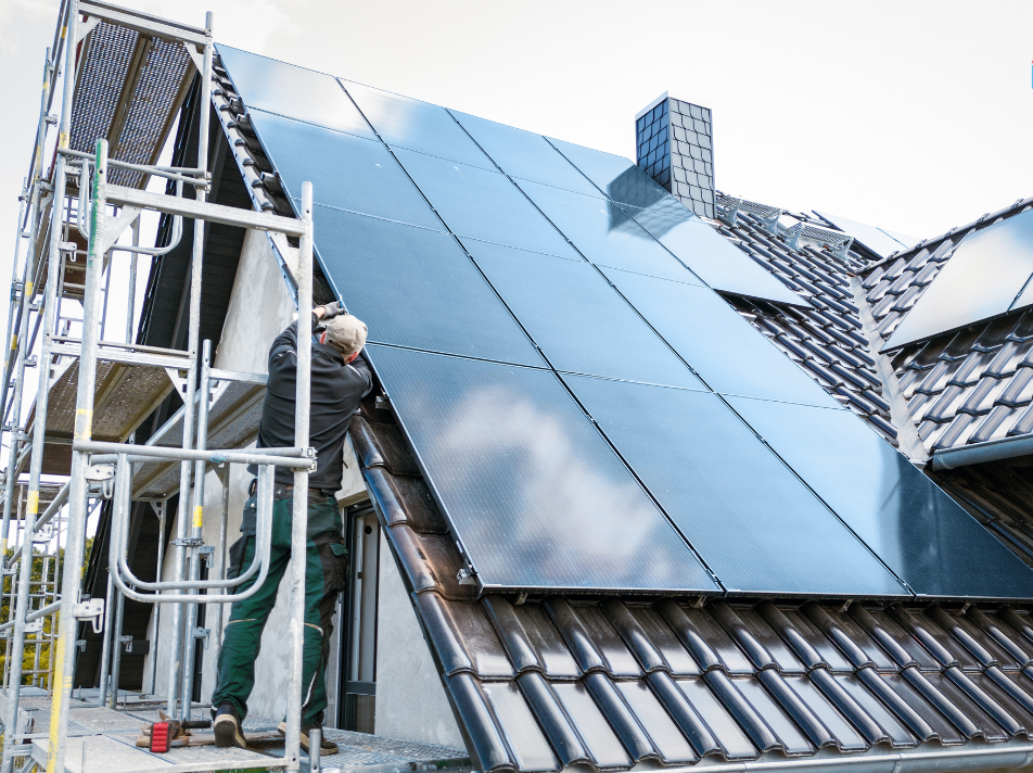 Engineer on scaffolding checking solar panels on a house roof